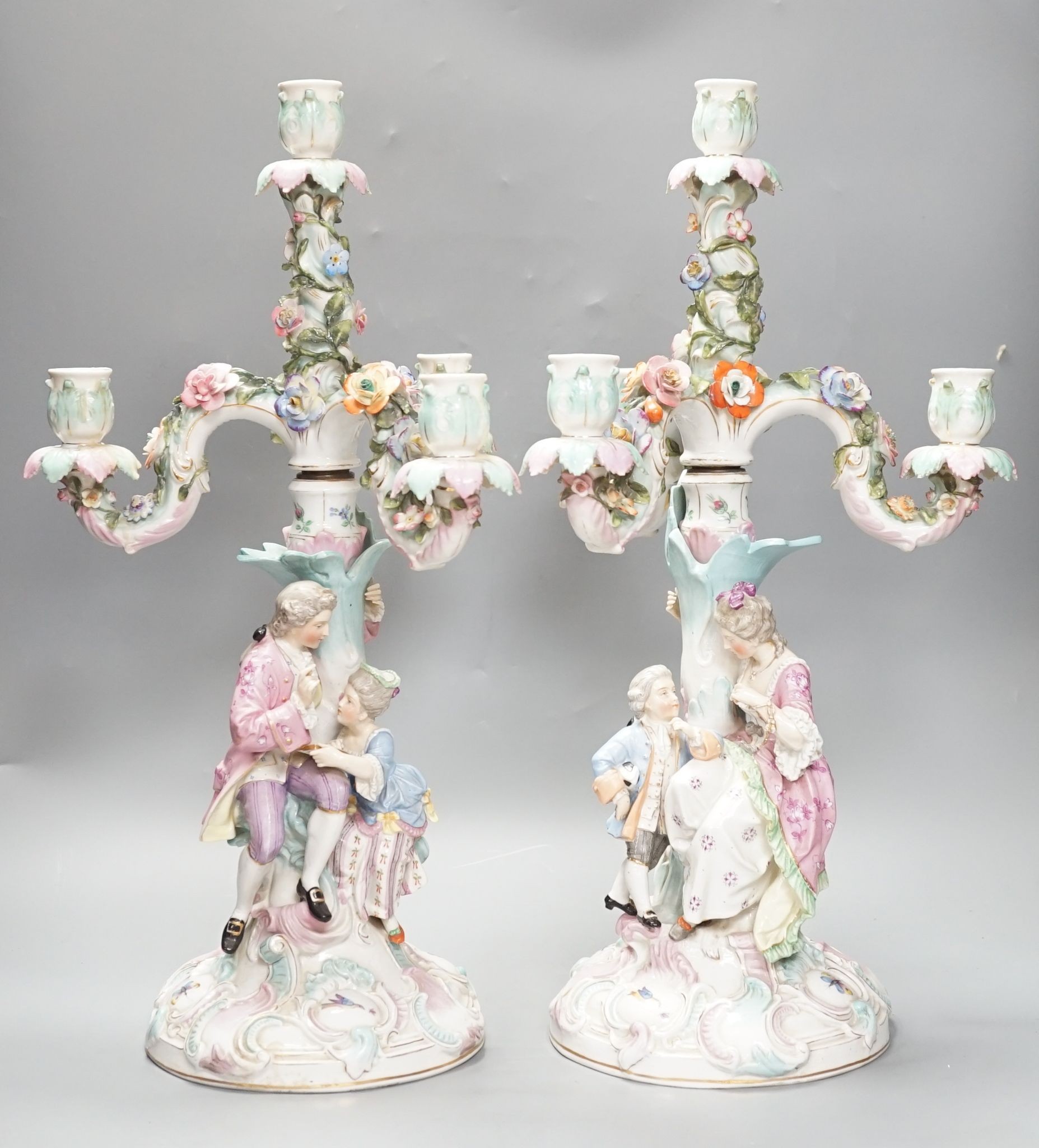 A pair of late 19th century German floral encrusted, figurative porcelain candelabra, 52 cms high.